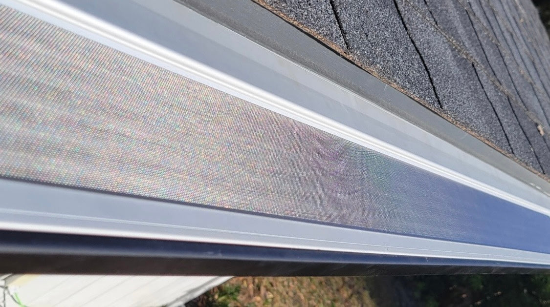 Close-up of micro-mesh gutter protection beside a roofline